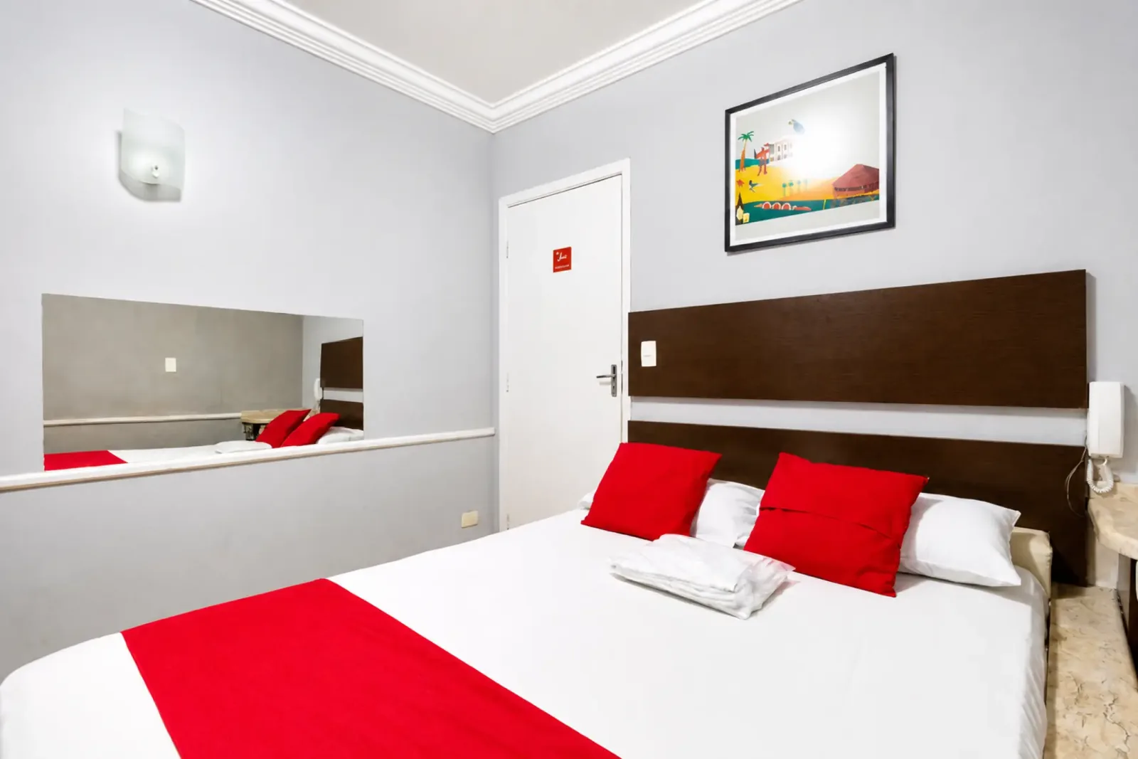 Suíte Superior com cama de casal, espelho e detalhes em vermelho
