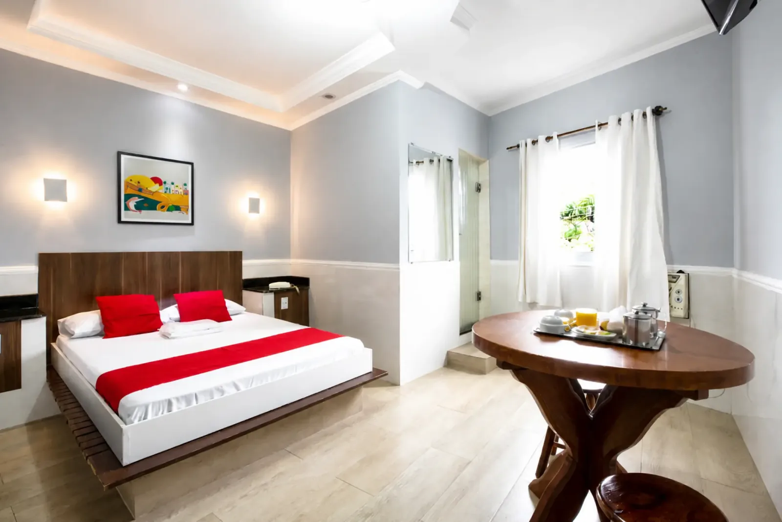 Suíte com cama de casal, mesa, cortinas e área de estar